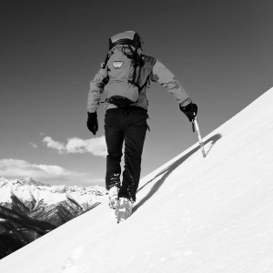 A climber on a snowy mountain climbing with the aid of an ice ax