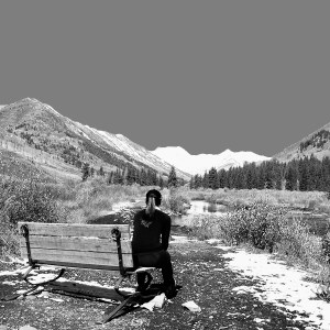 Dana Platin sits on a bench admiring the beautiful blue sky and snowy peaks in the distance