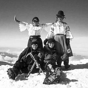 Four women, two Peace Corps volunteers including Dana Platin, and two indigenous Ecuadorian women (warmis) pose at the summit of Cotopaxi surrounded by snow