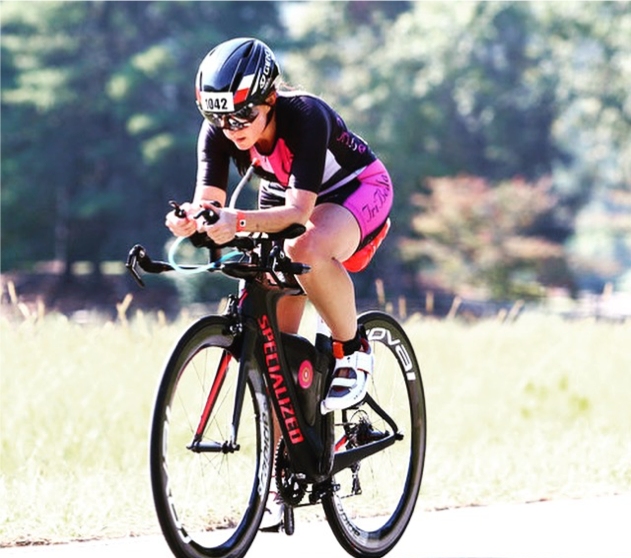 Dana Platin races on a bike in a pink and black outfit
